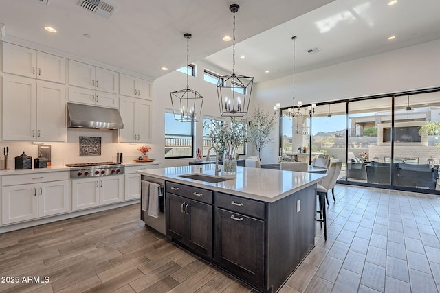 kitchen with sink, a healthy amount of sunlight, white cabinetry, and decorative light fixtures