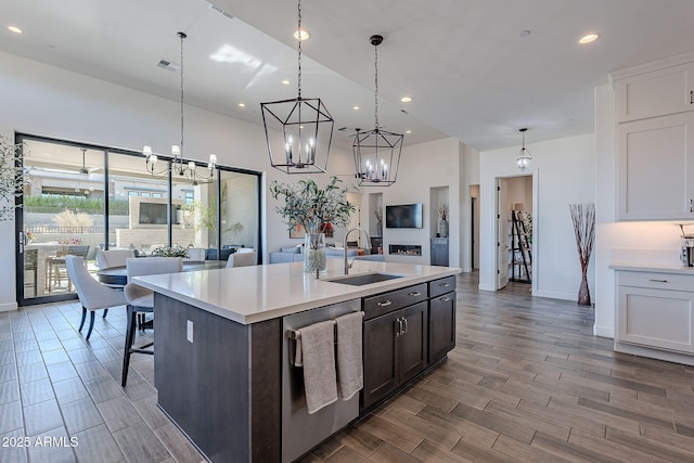 kitchen with sink, white cabinetry, dishwasher, and an island with sink