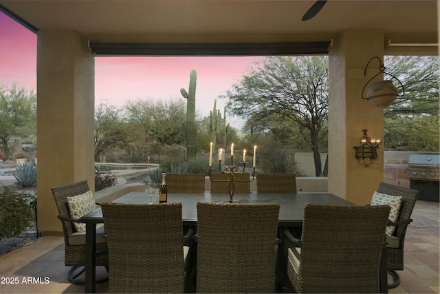 patio terrace at dusk with exterior kitchen, grilling area, and ceiling fan