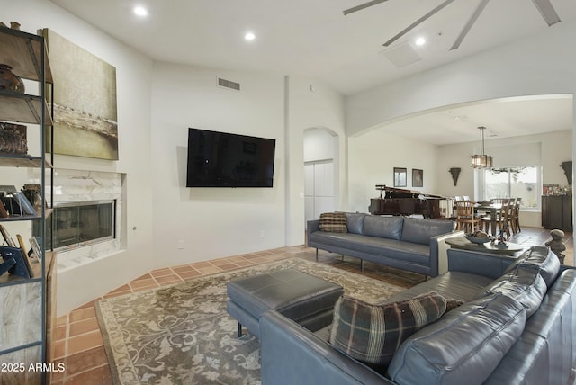 living room featuring a high end fireplace, a chandelier, and tile patterned flooring