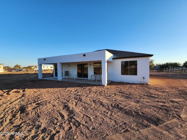 rear view of house with stucco siding, a patio, and fence