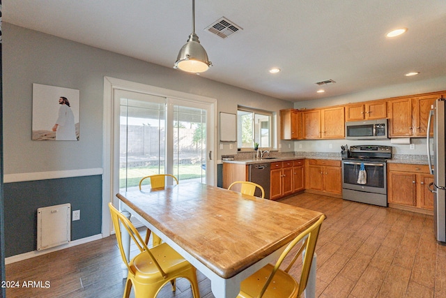 kitchen featuring sink, hanging light fixtures, light wood-type flooring, and appliances with stainless steel finishes