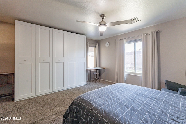 bedroom with ceiling fan, carpet, and a textured ceiling