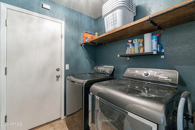 laundry room with light tile patterned flooring, separate washer and dryer, and a textured ceiling