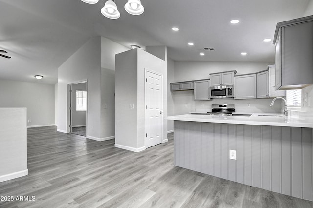 kitchen featuring sink, gray cabinetry, vaulted ceiling, kitchen peninsula, and stainless steel appliances