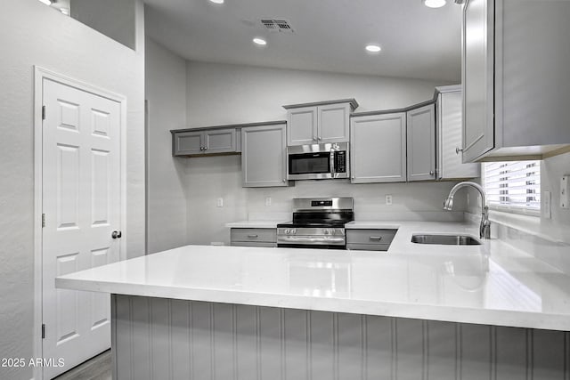 kitchen with gray cabinets, appliances with stainless steel finishes, sink, and kitchen peninsula