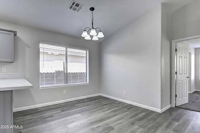 unfurnished dining area with lofted ceiling, dark hardwood / wood-style floors, and an inviting chandelier