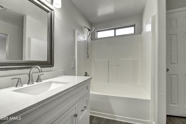 bathroom featuring wood-type flooring, vanity, and shower / bathing tub combination