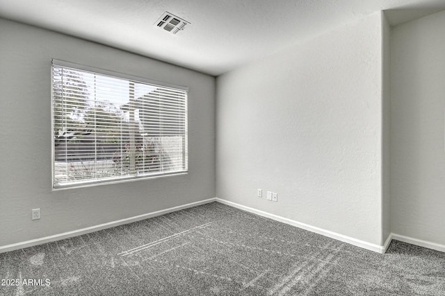 spare room featuring plenty of natural light and dark carpet