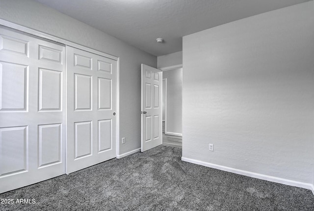 unfurnished bedroom featuring dark carpet and a closet