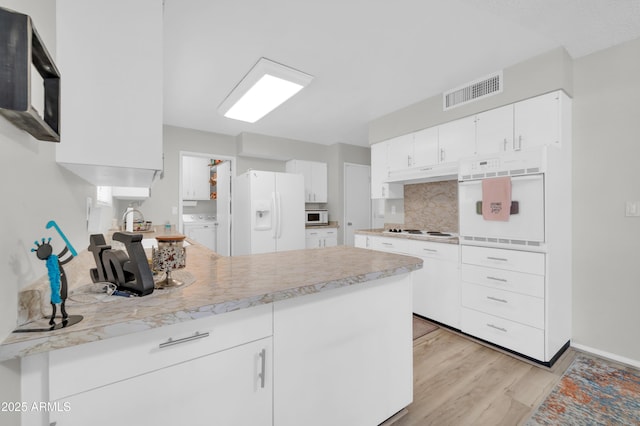 10873 W Clair Dr, Sun City, AZ 85351 - kitchen featuring white appliances, a peninsula, light wood finished floors, decorative backsplash, and washer / dryer