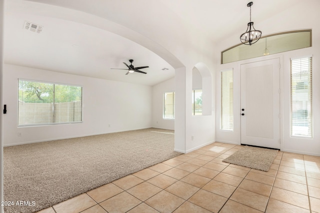 tiled foyer featuring ceiling fan with notable chandelier and vaulted ceiling