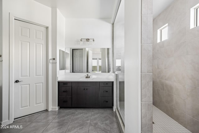 bathroom featuring tile patterned flooring, vanity, and a tile shower