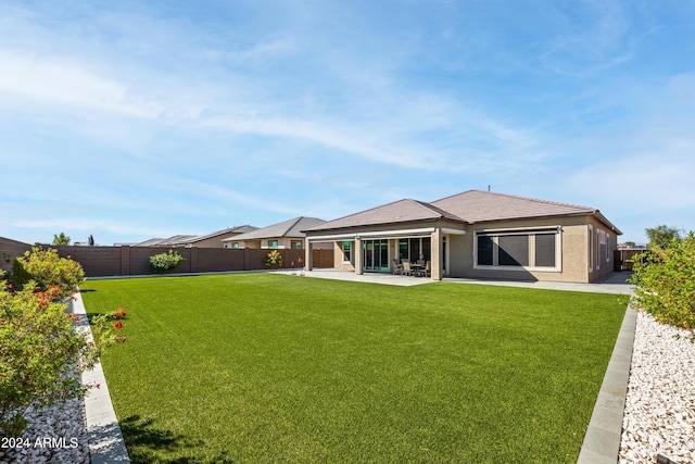 rear view of property with a lawn and a patio