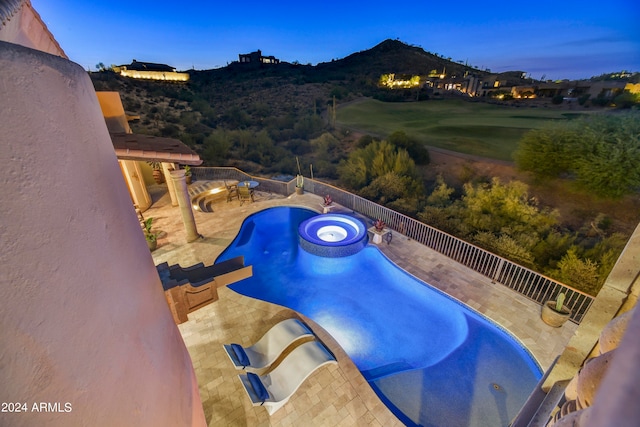 pool at dusk with a mountain view, an in ground hot tub, and a patio