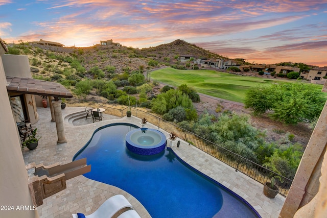 pool at dusk featuring an in ground hot tub and a patio