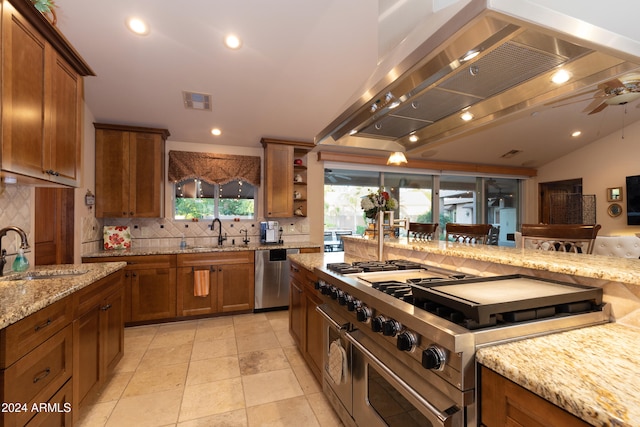 kitchen featuring light stone counters, island exhaust hood, sink, and appliances with stainless steel finishes