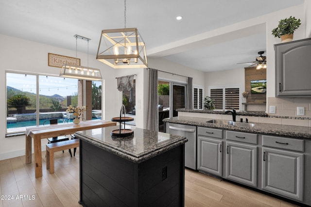 kitchen with pendant lighting, a center island, sink, stainless steel dishwasher, and gray cabinets