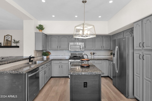 kitchen featuring pendant lighting, sink, gray cabinets, light wood-type flooring, and stainless steel appliances