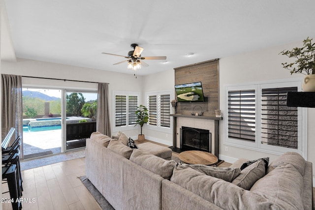 living room with ceiling fan, a fireplace, and light hardwood / wood-style flooring