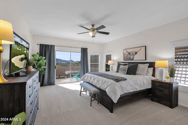 carpeted bedroom featuring access to exterior, ceiling fan, and a mountain view