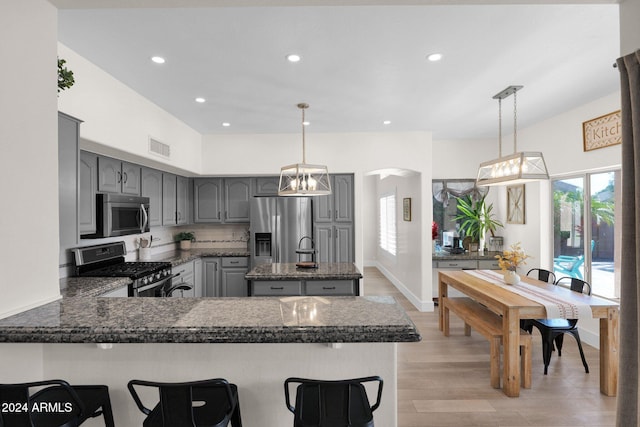 kitchen featuring gray cabinetry, decorative light fixtures, kitchen peninsula, and appliances with stainless steel finishes