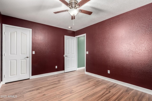 3235 S Bowman Rd, Apache Junction, AZ 85119 - unfurnished bedroom featuring a textured wall, wood finished floors, baseboards, ceiling fan, and a textured ceiling
