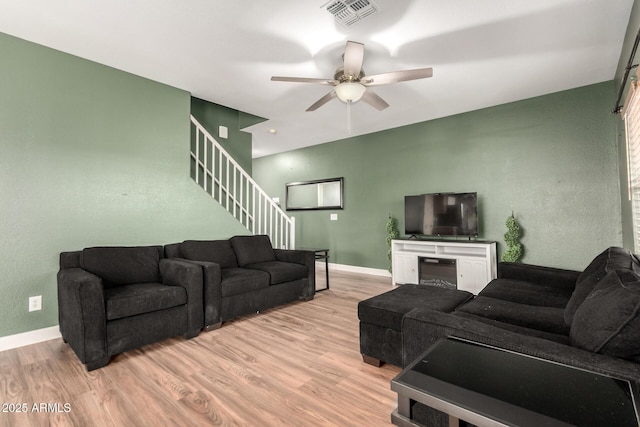 3235 S Bowman Rd, Apache Junction, AZ 85119 - living area featuring light wood-style floors, ceiling fan, stairway, baseboards, and a glass covered fireplace
