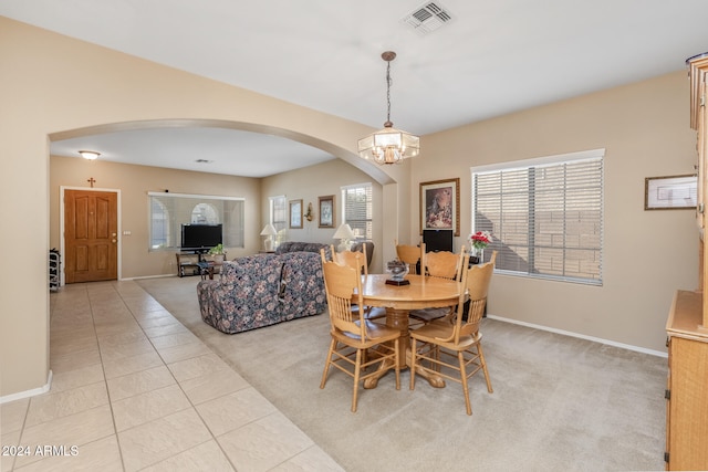 dining space with light carpet and an inviting chandelier