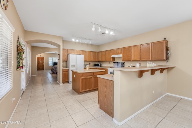 kitchen featuring a wealth of natural light, white fridge with ice dispenser, light tile patterned flooring, and a kitchen island