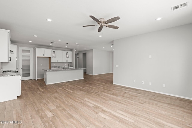 unfurnished living room featuring sink, light hardwood / wood-style flooring, and ceiling fan