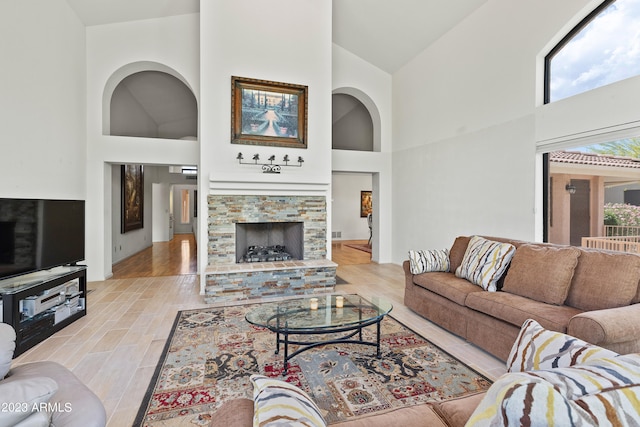 living room featuring light hardwood / wood-style floors, high vaulted ceiling, and a fireplace