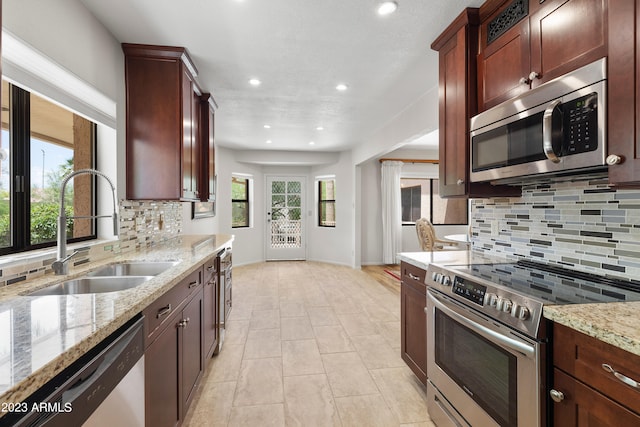 kitchen with light stone countertops, backsplash, stainless steel appliances, sink, and light tile floors