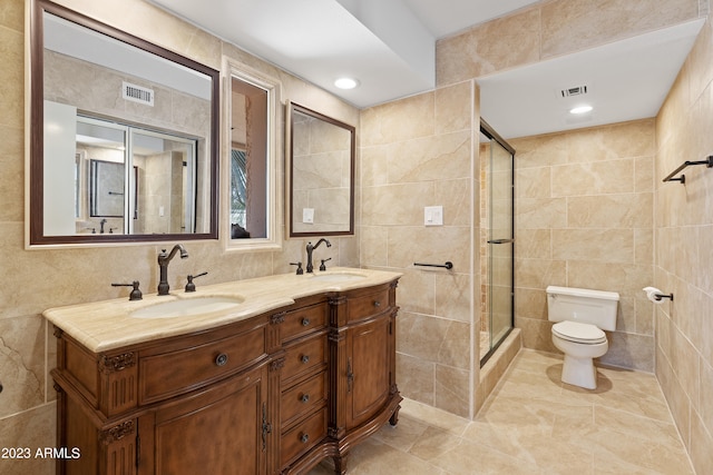 bathroom featuring double vanity, tile floors, tile walls, and toilet