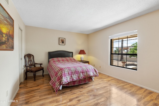 bedroom with light hardwood / wood-style flooring and a textured ceiling