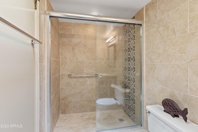 bathroom featuring a shower with door, toilet, and tile walls