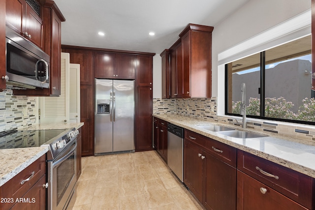 kitchen with light stone counters, backsplash, light tile floors, and stainless steel appliances