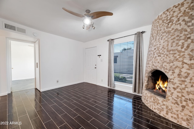 unfurnished living room featuring a large fireplace and ceiling fan