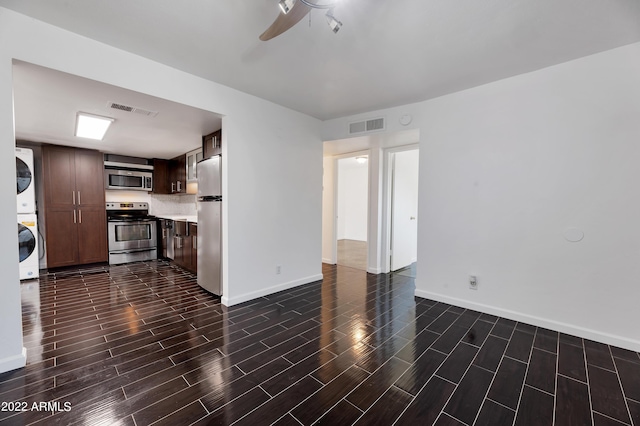 unfurnished living room featuring ceiling fan and stacked washer and dryer