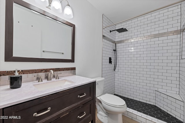 bathroom featuring vanity, toilet, and a tile shower