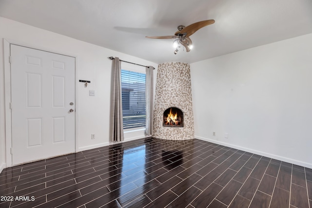 unfurnished living room with a large fireplace and ceiling fan