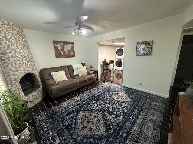 living room with ceiling fan and stacked washer / drying machine