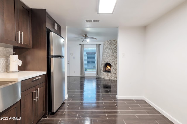 kitchen featuring decorative backsplash, dark brown cabinetry, stainless steel refrigerator, and ceiling fan