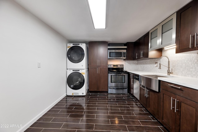 kitchen with sink, stacked washing maching and dryer, stainless steel appliances, and dark brown cabinetry