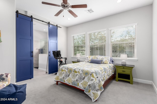 bedroom featuring a barn door, ceiling fan, light carpet, and multiple windows