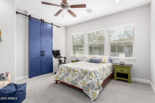 carpeted bedroom featuring multiple windows, a barn door, and ceiling fan