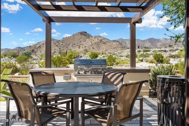 balcony with a pergola, grilling area, a mountain view, and an outdoor kitchen