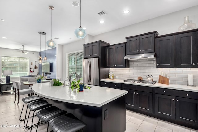 kitchen featuring ceiling fan, an island with sink, hanging light fixtures, and appliances with stainless steel finishes