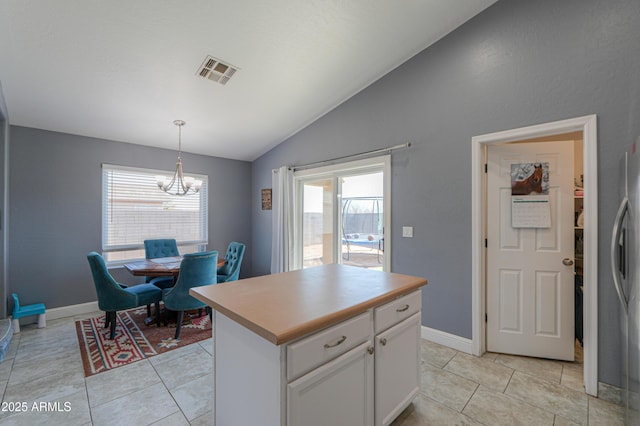 kitchen featuring vaulted ceiling, stainless steel refrigerator, a kitchen island, pendant lighting, and white cabinets