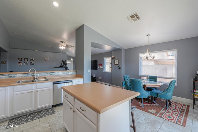 kitchen with sink, white cabinets, a kitchen island, decorative light fixtures, and stainless steel dishwasher